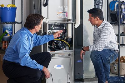 65df8c11f3e4c468cbd351a5_furnace repair vs replacement – Copy HVAC technician explaining furnace repair and maintenance to a homeowner in Phoenix, AZ